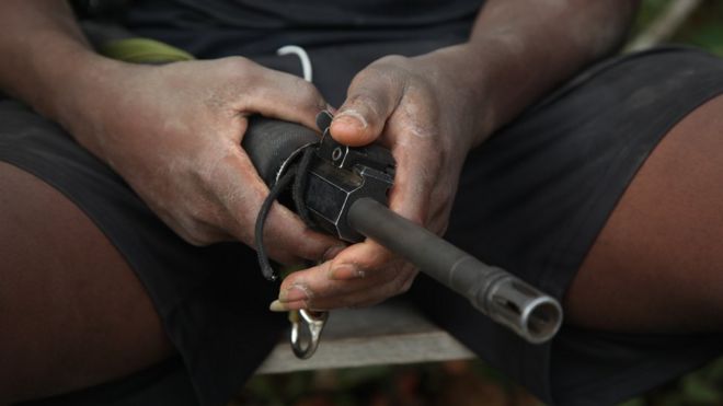 Un guerrillero sostiene un fusil en sus manos.