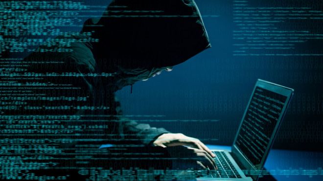 Un hombre en la sombra con pinta maliciosa entrando en un computador.
