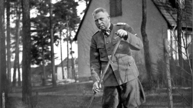 Karl Niemann en su uniforme limpiando el jardín.
