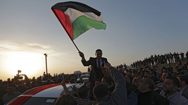 Palestinians hold up a groom waiving a Palestinian flag near the border with Israel