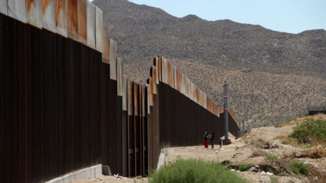 A Mexican family stands next to the border wall between Mexico and the United States, in Ciudad Juarez, Mexico on May 23, 2017