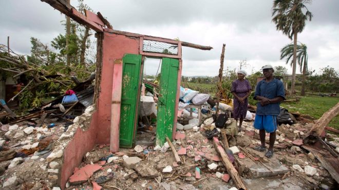 Saintanor Dutervil stands with his wife in the ruins of their home destroyed by Hurricane Matthew in Les Cayes, Haiti