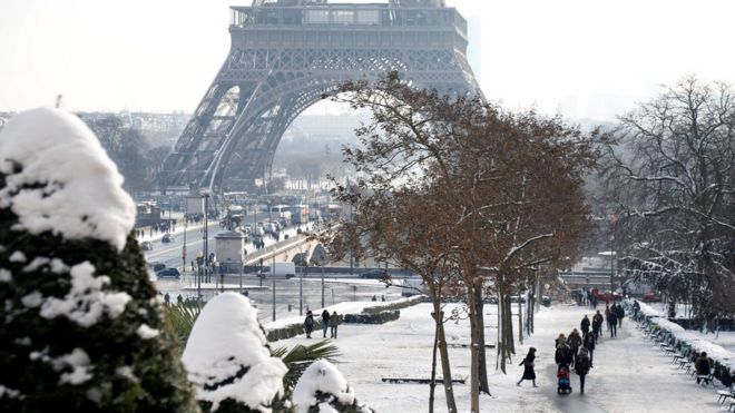 People walk on the snow-covered Trocadero gardens near the Eiffel Tower in Paris, as winter weather with snow and freezing temperatures arrive in France, February 8, 2018