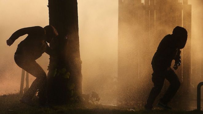 Two protesters outlined against the smoke during riots in Hamburg