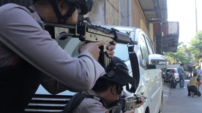 Police aim their weapons at a man who was being searched by other police officers following an explosion at nearby police headquarters in Surabaya, Indonesia May 14, 2018 in this photo taken by Antara Foto