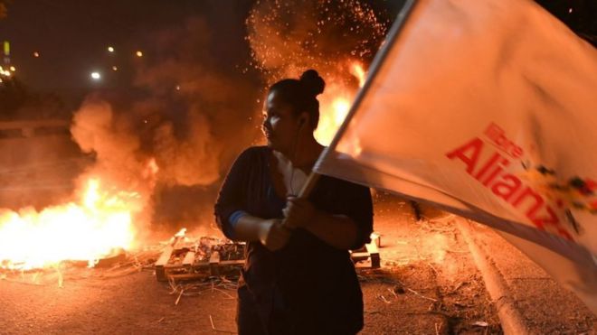 Mujer con una bandera que dice Libre Alianza