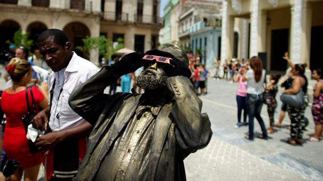 A street performer looks towards the sky as enthusiasts gather in Old Havana for the partial solar eclipse in Cuba August 21, 2017.