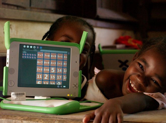 Madagascar, 2010. Children hold their laptops whilst smiling.to deploy small laptops in