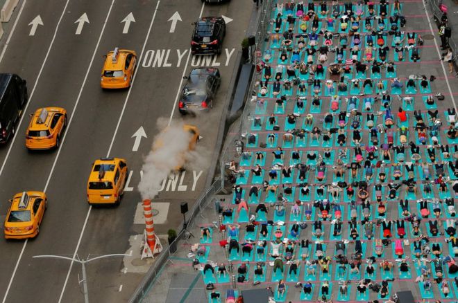 Decenas de personas practican yoga en el distrito de Times Square, en Nueva York, durante el solsticio de verano.