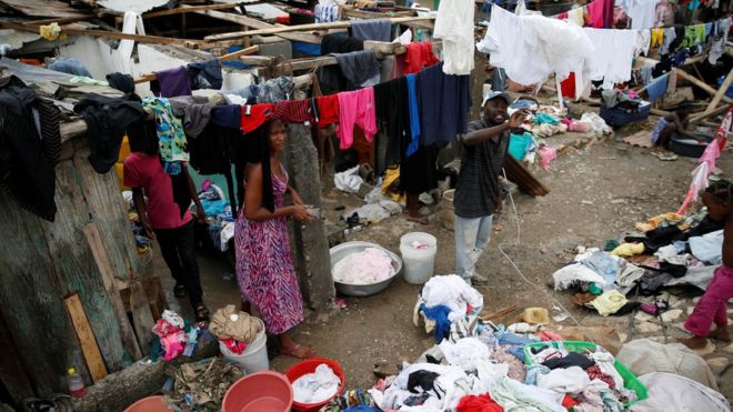 People wash their clothes in front of their partially destroyed houses after Hurricane Matthew passes Jeremie in Haiti