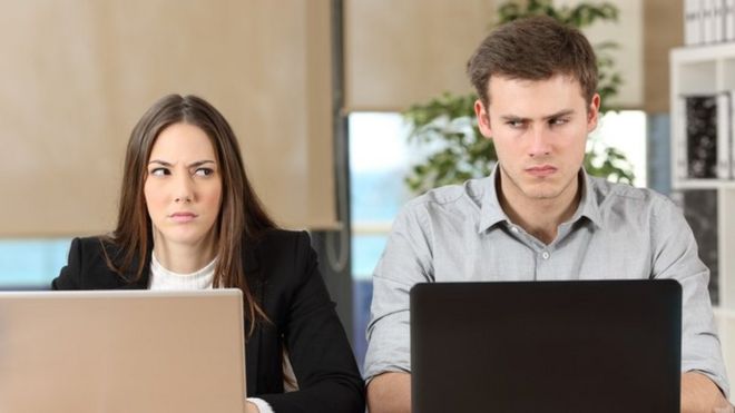 Dos personas sentadas lado a lado, con mirada recelosa hacia la otra