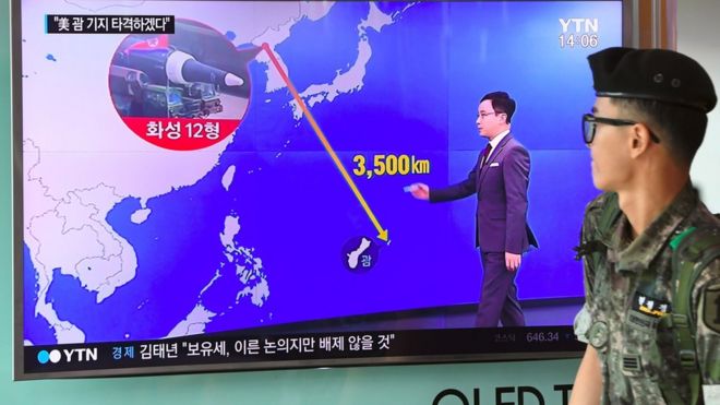South Korean soldier walks past TV showing a graphic of the distance between North Korea and Guam at a railway station in Seoul on 9 August 2017