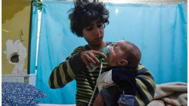 Menino põe máscara de oxigênio em recém-nascido após suposto ataque em Douma em janeiro de 2018