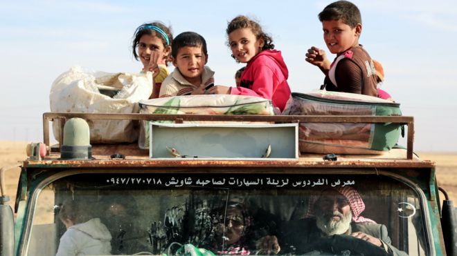Children sit on top of a truck carrying Syrian refugees