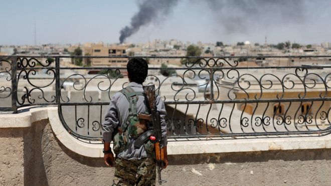 Un combatiente kurdo observa Raqqa justo después de un ataque aéreo sobre la ciudad.