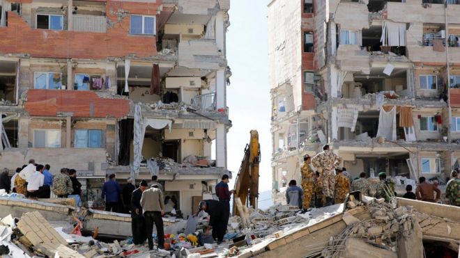 Iranian people and soldiers stand around damaged buildings in the city of Sarpol-e Zahab in Kermanshah Province, Iran on13 November 2017.