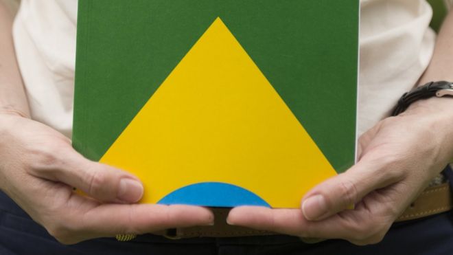 Mulher segura cÃ³pia da ConstituiÃ§Ã£o, com bandeira do Brasil na capa