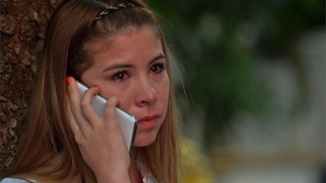 Una joven habla por teléfono con los ojos enrojecidos.