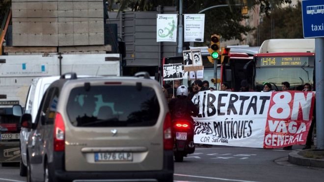 Protesters hold a banner that reads "Freedom for political prisoners" as they block a road during a strike in Barcelona
