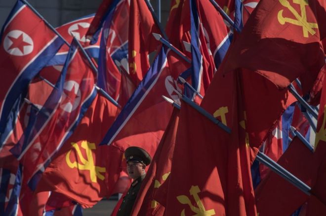 Um soldado do Exército Popular da Coréia (KPA) está entre as bandeiras antes de uma cerimônia de abertura para o desenvolvimento da habitação da rua Ryomyong em Pyongyang em 13 de abril de 2017.