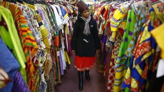 Woman looks at rails of African clothing