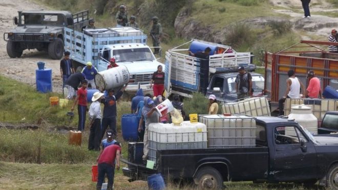 People fill large drums of fuel from a clandestine outlet c, in the state of Puebla, Mexico, 23 October 2017