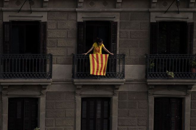 Mujer en un balcón de Barcelona con la bandera catalana.