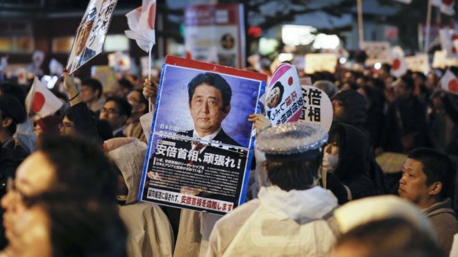 A voter supporting Japanese Prime Minister Shinzo Abe and his ruling Liberal Democratic Party raises a placard reading "Go, Prime Minister Abe" during Abe's final campaign of the Lower House election outside Akihabara JR Station in Tokyo, Japan, 21 October