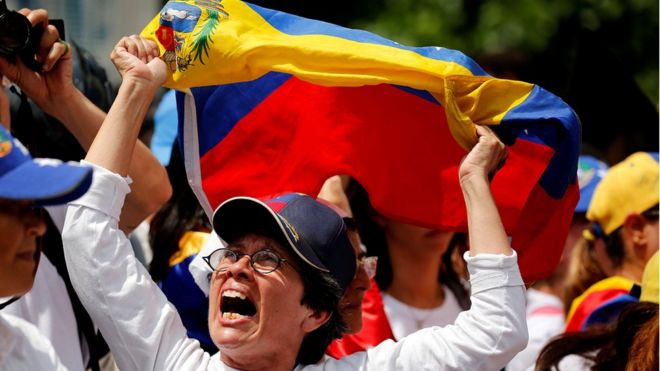 Una mujer protesta con la bandera de Venezuela entre sus manos.