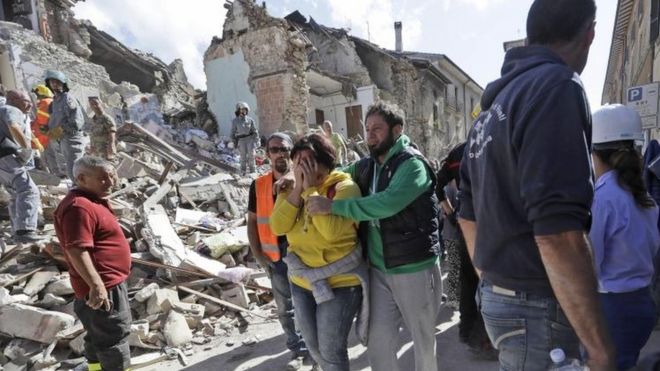 Una mujer llora, detrás el derrumbe que provocó el terremoto.