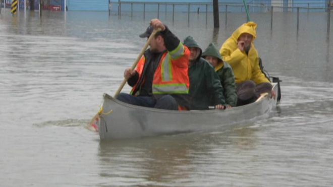 People row a boat through floodwaters