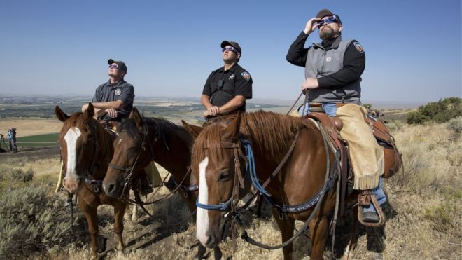 The Madison County Sheriff's Mounted Patrol watch the eclipse atop horses on Menan Butte on August 21, 2017 in Menan, Idaho.