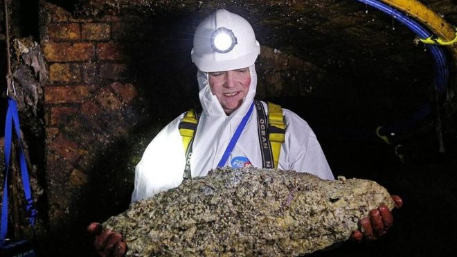 Um técnico de esgoto segura um 'fatberg' em um túnel de Londres