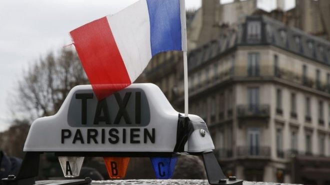 A French flag waves above a striking French taxi as drivers continue their national protest about competition from private car ride firms like Uber (27 January 2016)
