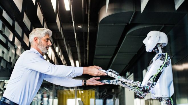 A man and a robot holding hands