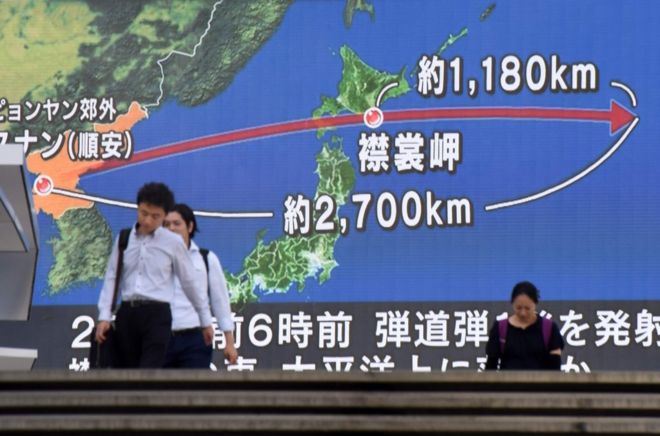 在東京街頭，行人走過展示有日本和朝鮮半島地圖的巨大屏幕。