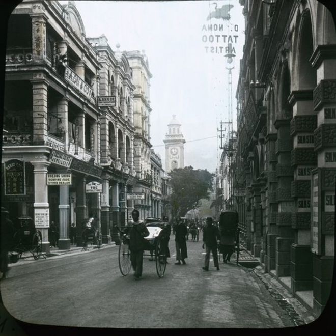 Nhìn về phía đông từ phố Li Yuen East sang Đường Queen's Road Central. Tháp đồng hồ ở Phố Pedder Street, có thể nhìn thấy ở cuối đường, bị phá đi từ năm 1913.