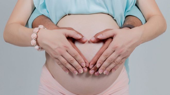 Pregnant woman with hands around her bump