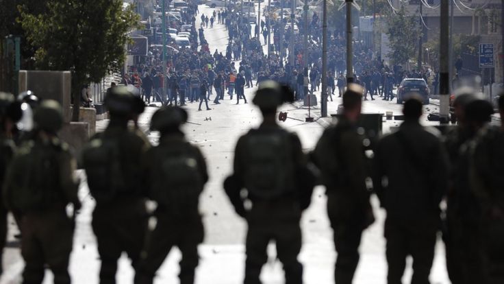 Israeli soldiers watch on as Palestinians gather in Bethlehem on 7 December 2017