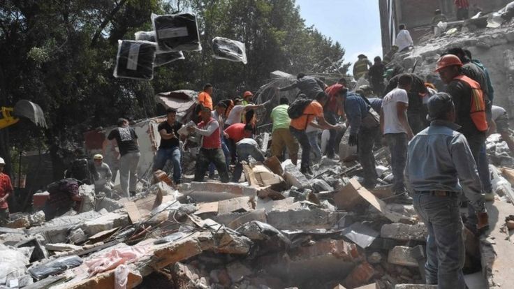 Personas recogiendo escombros de un edificio