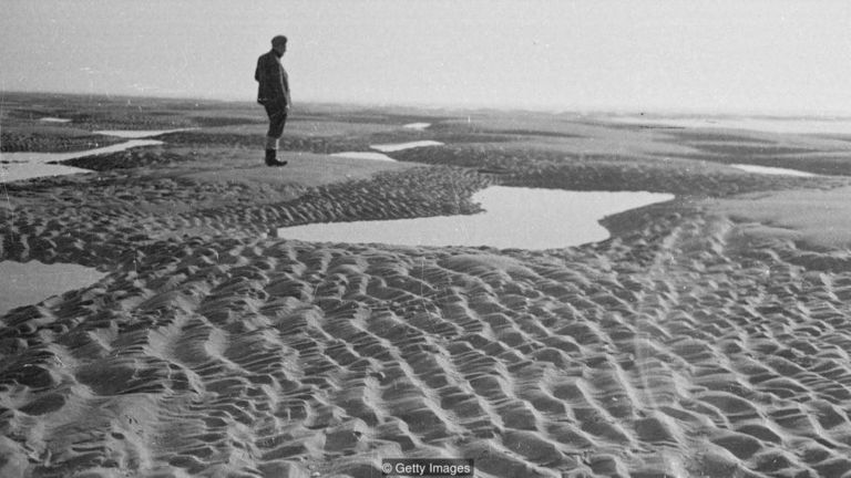 A local stands on the Sands in 1948; as the tide rises, hidden pools of quicksand and flooding sea make it as dangerous to stand on as it is to sail past