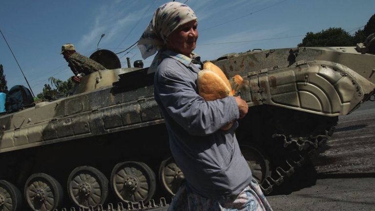 A Georgian woman carries humanitarian relief bread past a Russian checkpoint on 17 August 2008 in Gori, Georgia