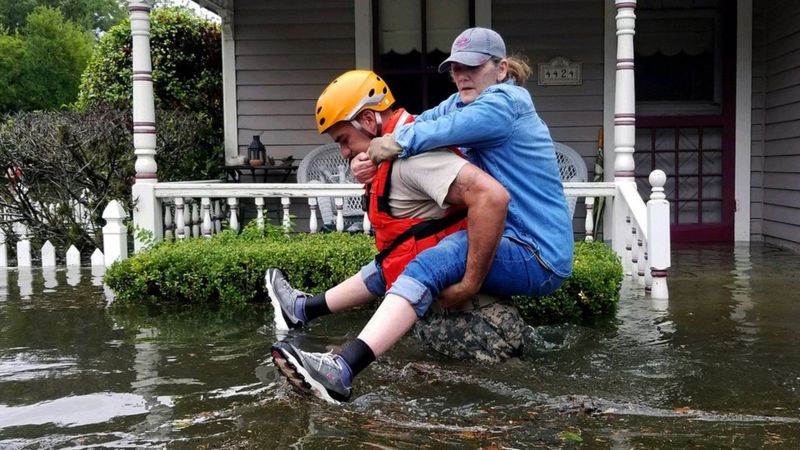 Un rescatista carga a una mujer en medio de una inundación tras el paso de la tormenta Harvey en Texas (EE.UU.)