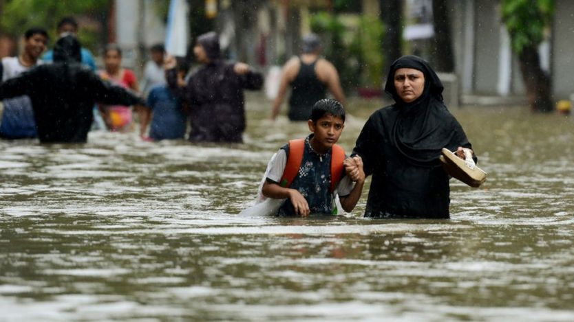 Una mujer camina con su hijo por una calle inundada en Mumbai.