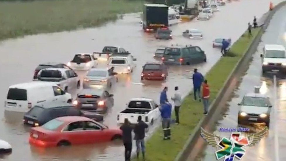 People standing on a central reservation look at submerged vehicles on a flooded road during stormy weather in Durban, South Africa, 10 October 2017