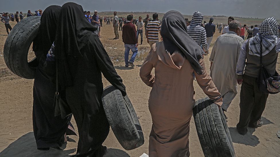 Palestinian female protesters carry tires during clashes after protests near the border with Israel in the east of Jabaliya in the northern Gaza Strip