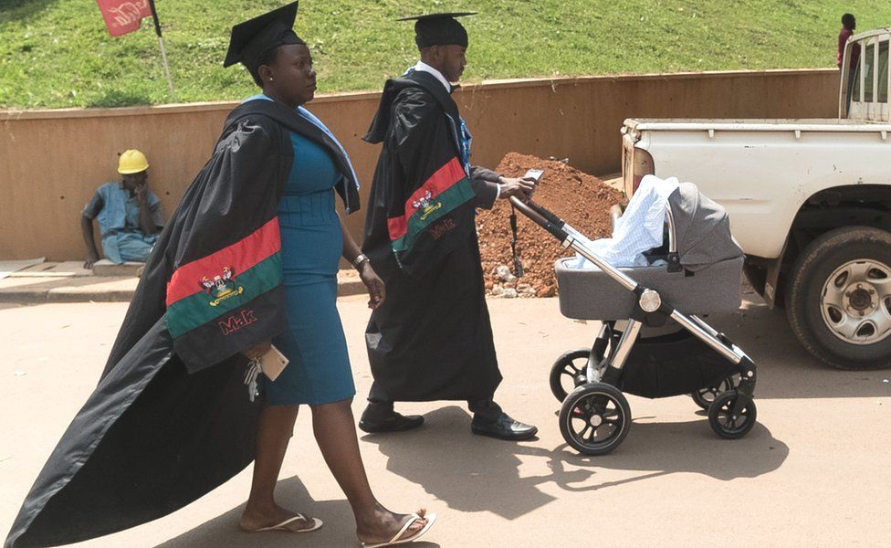 Graduates push a stroller and walk in a campus after the 68th graduation ceremony, where more than 14 000 students received degrees, at Makerere University in Kampala, Uganda, on January 19, 2018