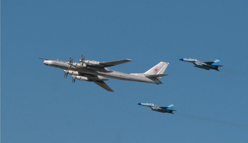Pesawat pembom startegis TU-95 dikawal pesawat tempur MiG-29 dalam sebuah demponstrasi terbang untuk memperingati ulang tahun Angkatan Udara Rusia.