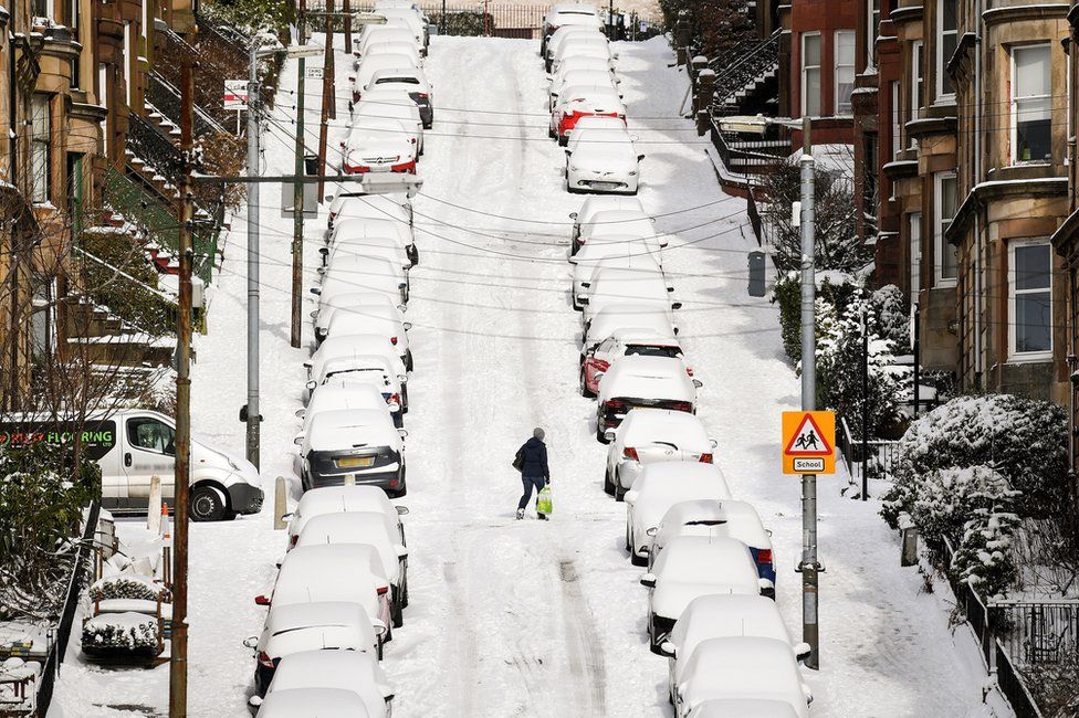 Members of the public make their way through the snow in a street in Glasgow, Scotland