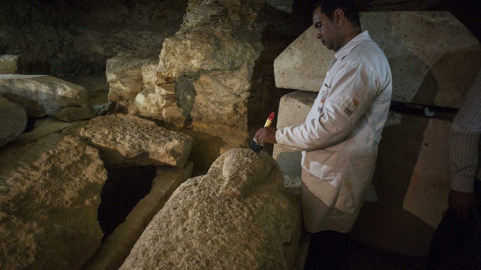 Un arqueólogo egipcio trabaja en un sarcófago en la reciente necrópolis descubierta.